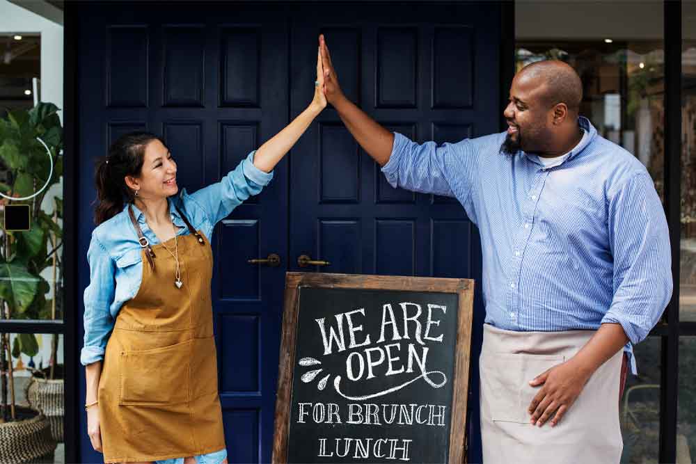 Two business owners giving a high five in celebration of opening a new location which will require a new website design